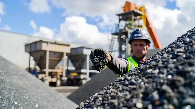 Quality control engineer inspecting raw aggregates at an asphalt batching plant site